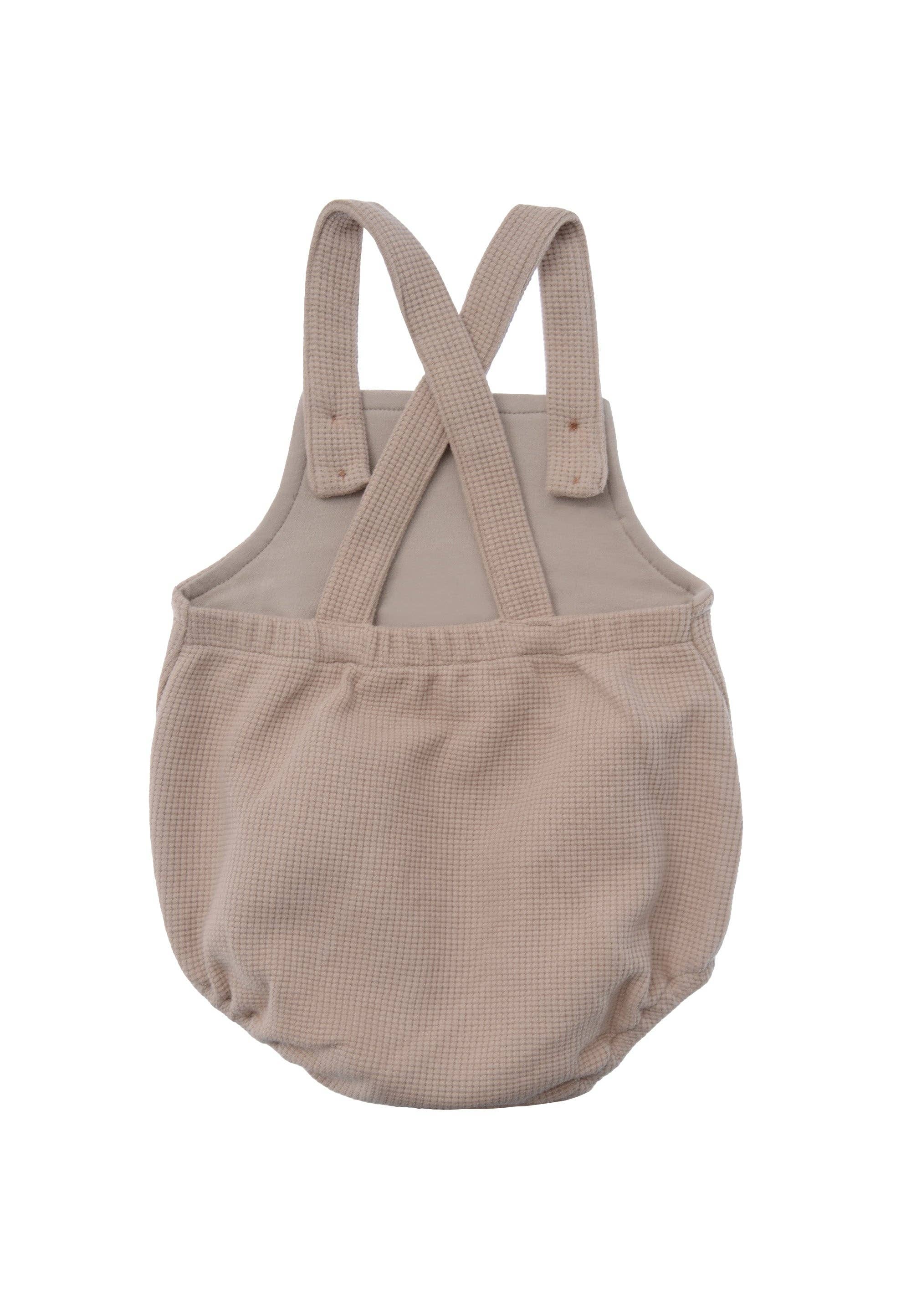 Zeitlose Baby Latzhose aus Waffel Piqué in Beige, weiches Material mit Baumwolle, langlebig, stylisch und angenehm zu tragen.