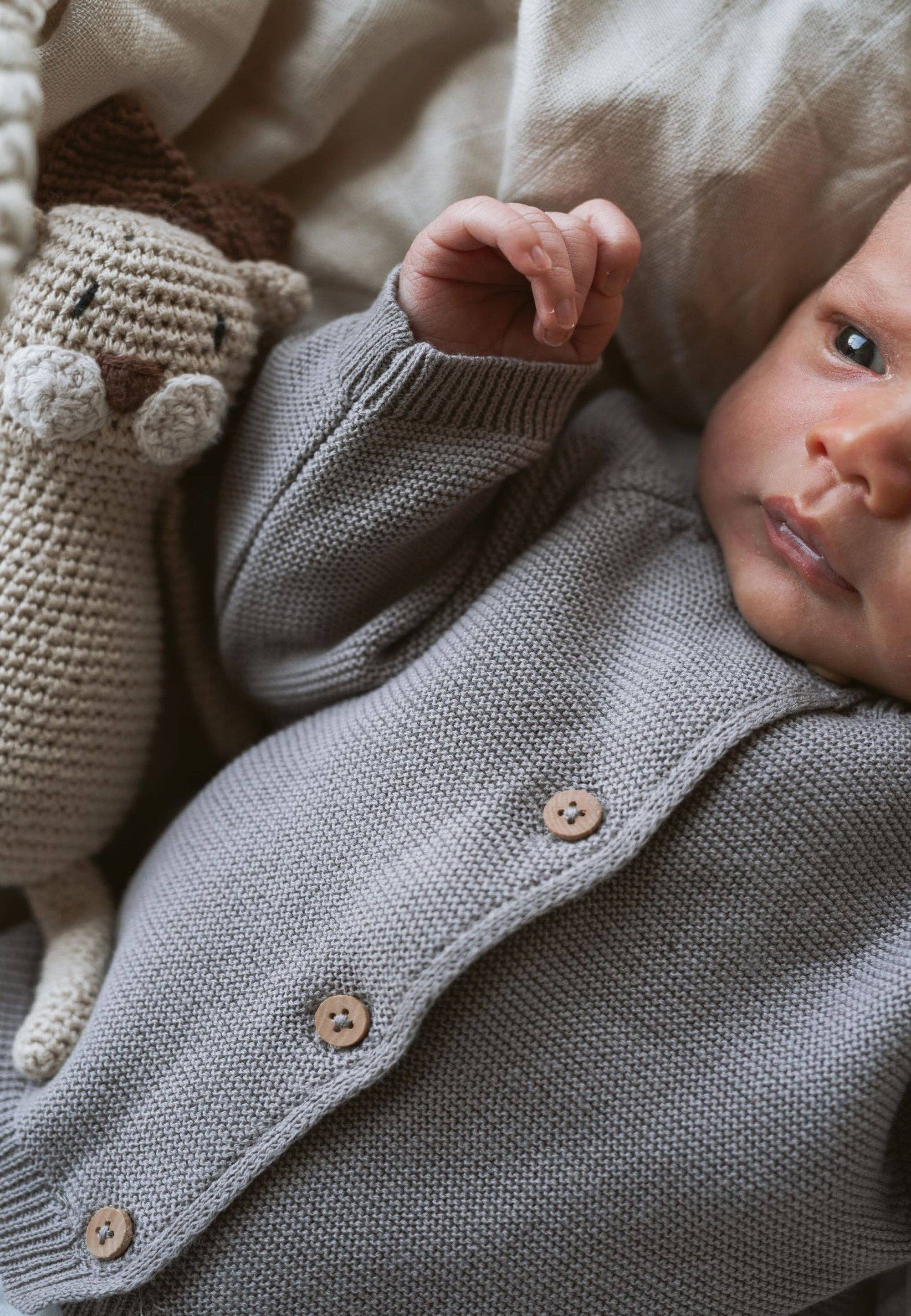 Baby Strickjacke in Taupe mit Holzknöpfen, aus 100% Baumwolle, weiches Strickbild, Raglanärmel, angenehm warm und bequem.