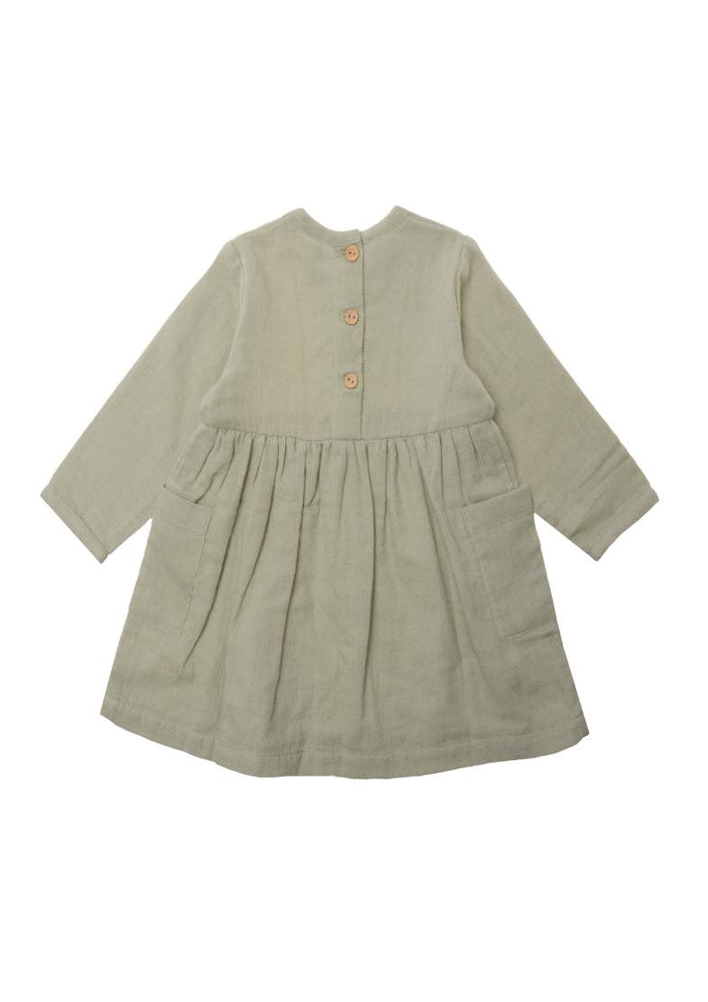 Langärmliges Musselin-Kleid für Mädchen in Schilf mit aufgesetzten Taschen und Holzknöpfen, aus 100% Baumwolle.